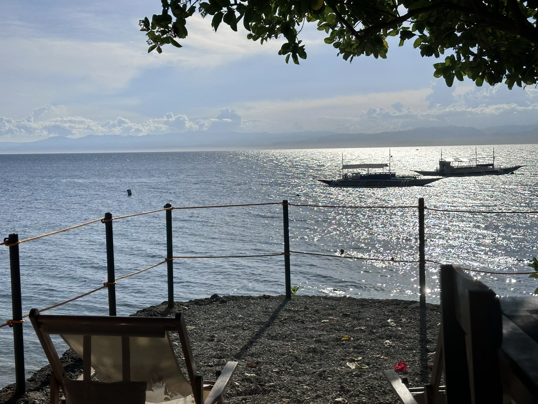 Beach chair overlooking the sparkling sea with bangka boats