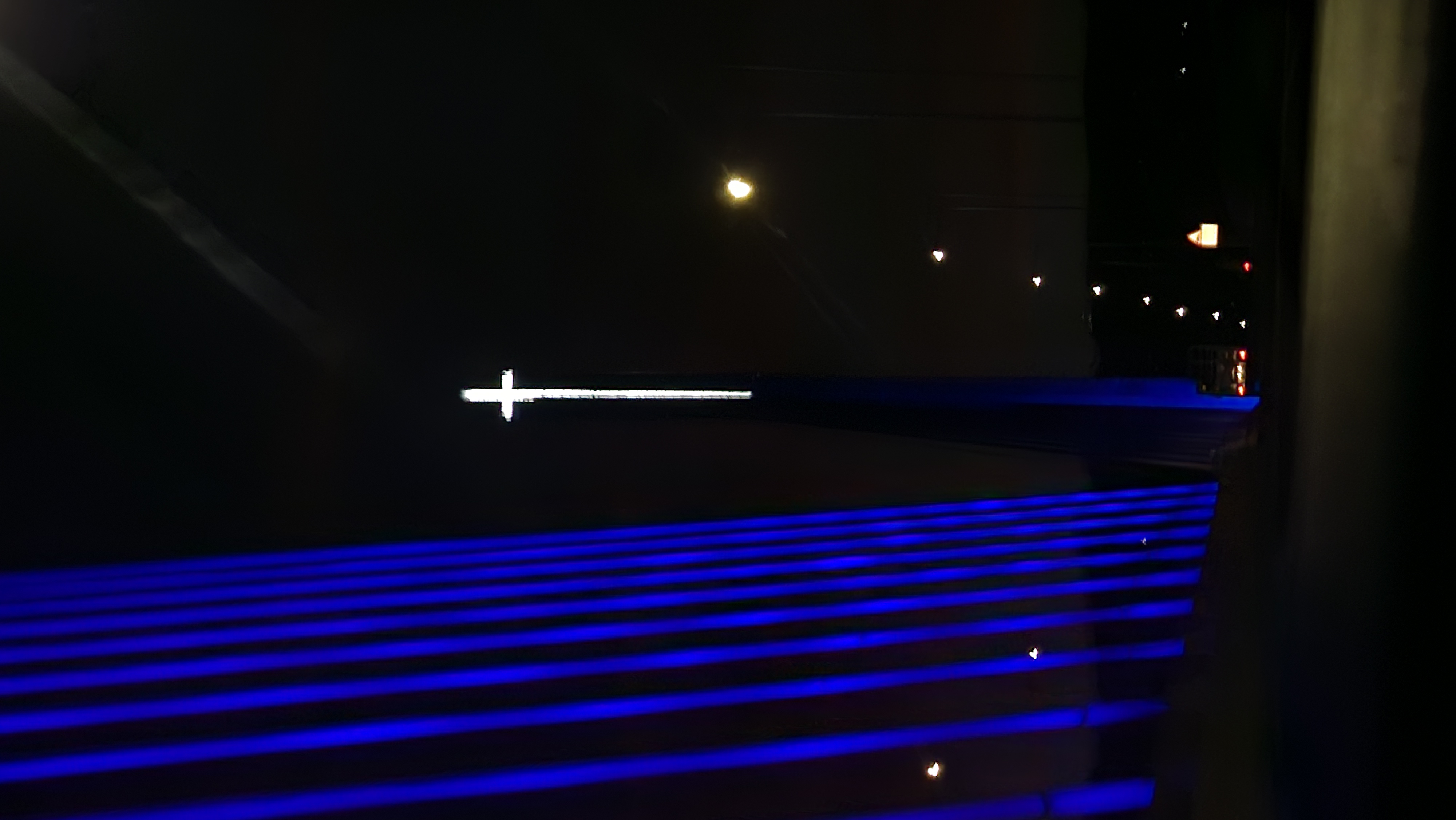 Illuminated cross with blue bridge cables at night