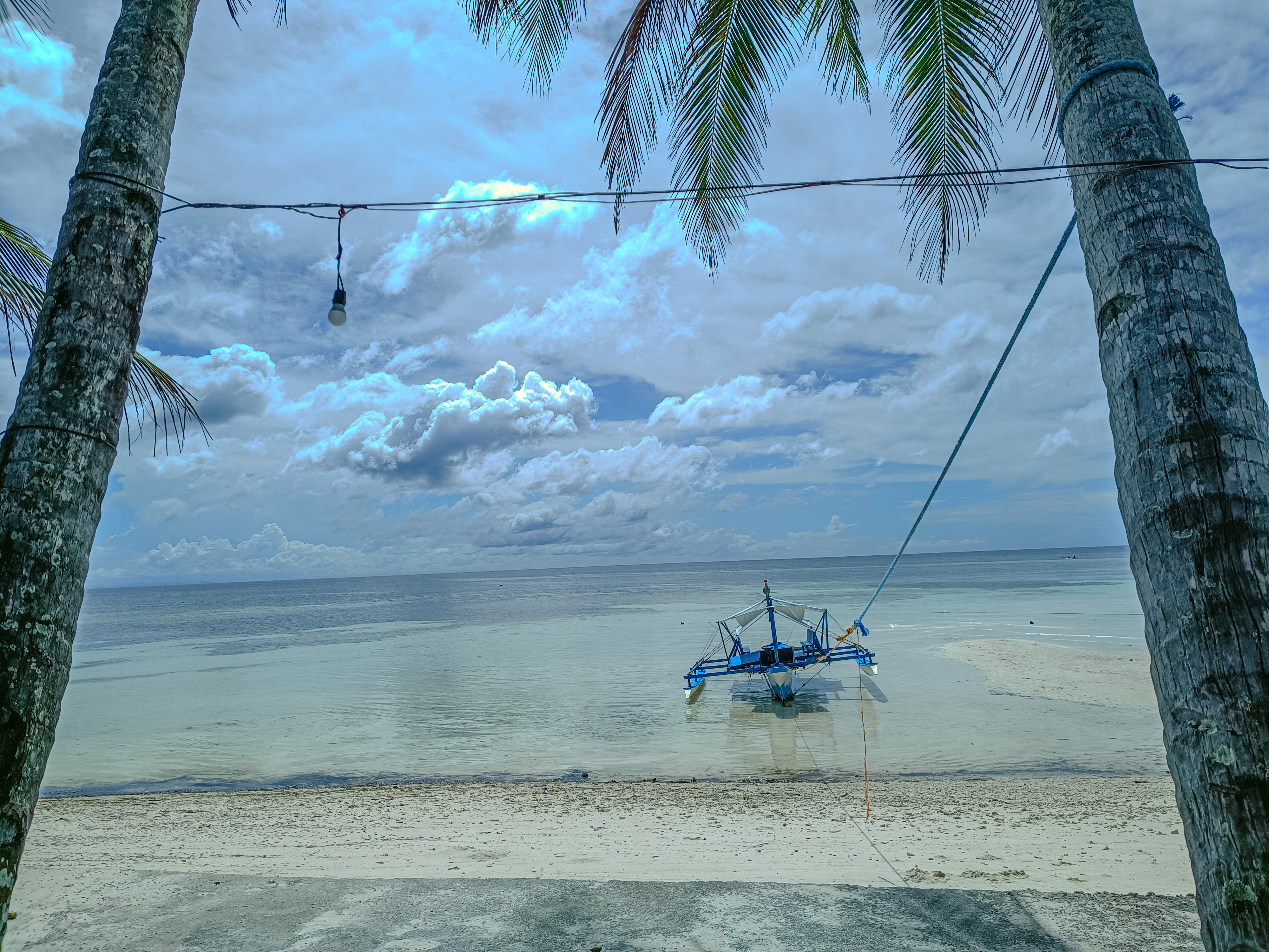 Bangka boat on the shore framed by coconut palms