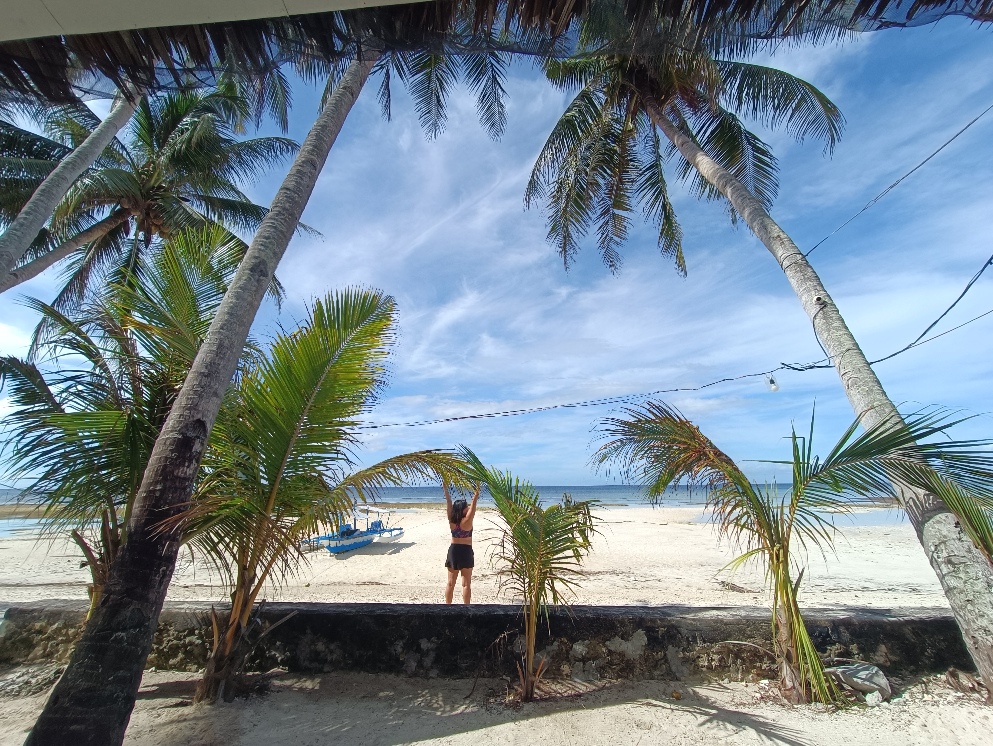 Person standing on the beach with arms raised